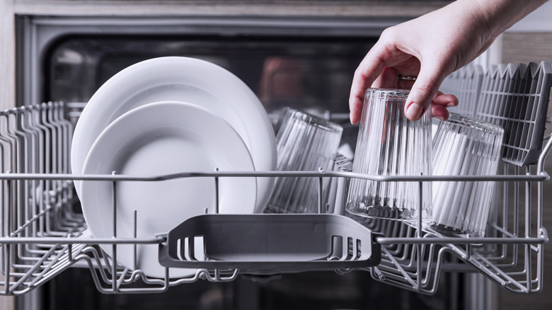 Hand unloading glasses from dishwasher