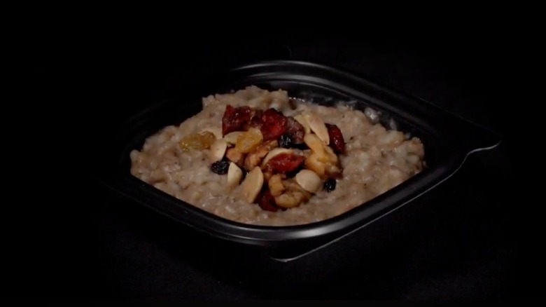 Multigrain oatmeal with fruit and nut toppings in black plastic dish