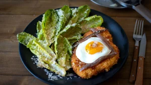 Kuhajte kot pravi kuhar: piščančji šnicl z ocvrtim jajcem in solato Caesar