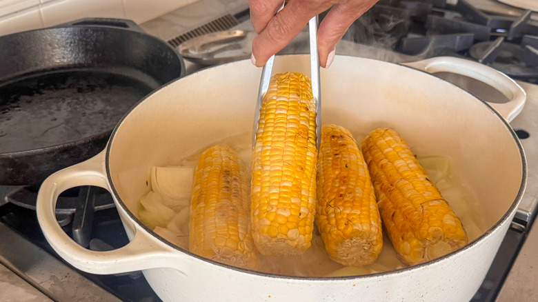 hand addiing corn to pot