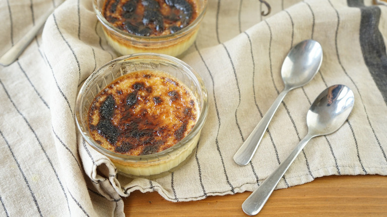Crème brûlées in glass ramekins on striped linen
