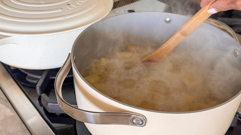 hand stirring potatoes in pot