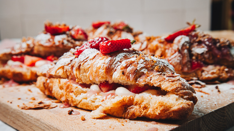 A group of strawberry cheesecake croissants on a cutting board.