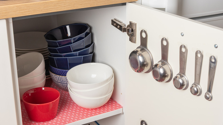 Measuring cups and spoons hanging inside cabinet door