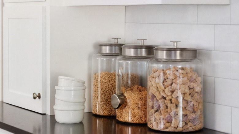 Glass food canisters, one with measuring cup attached