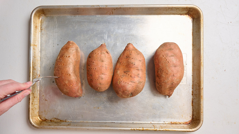 using a fork to poke holes into sweet potatoes