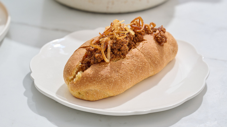 Chili dog topped with crunchy onions on a plate
