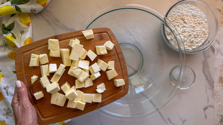hand adding butter to bowl