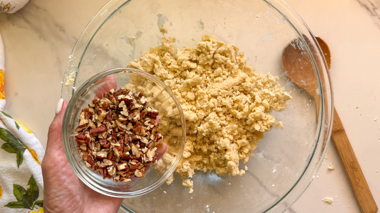 hand adding pecans to bowl