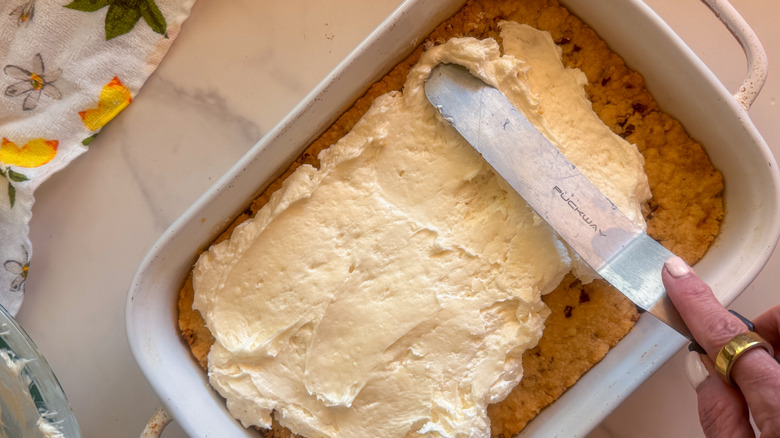 hand spreading cream cheese layer