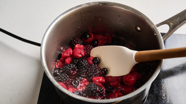 stirring berries in a saucepan with a spatula
