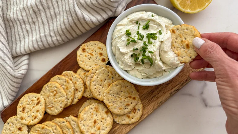 hand scooping dip with cracker