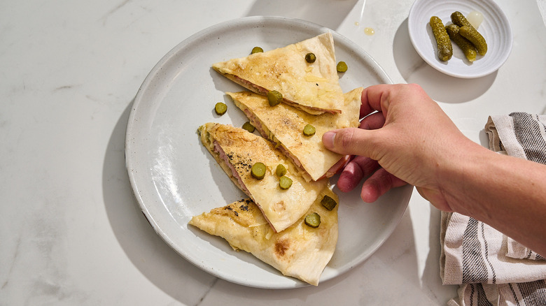 hand reaching for a quesadilla slice on a plate