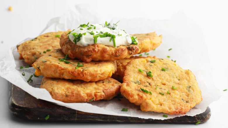 Air Fryer Corn Fritters with creamy sauce stacked on wooden board