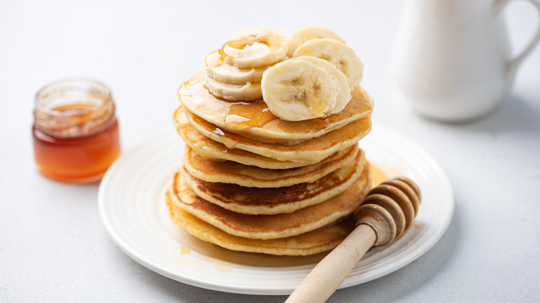 Stack of pancakes topped with fresh bananas