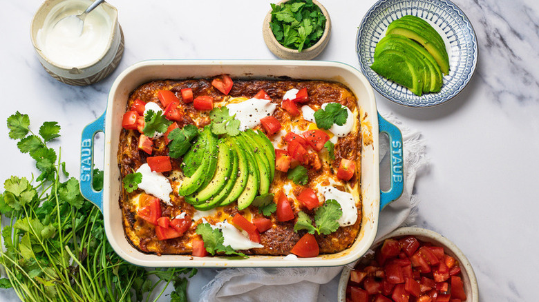 Tortilla breakfast casserole in baking dish, topped with sliced avocado