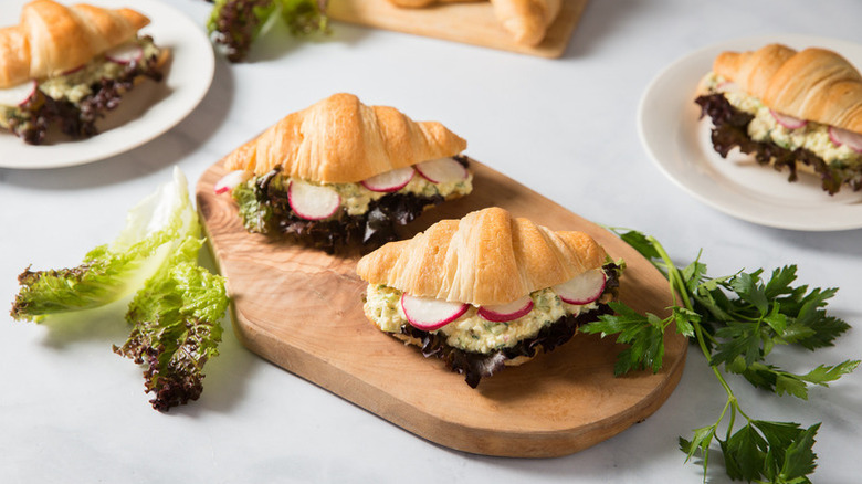 Egg salad croissant sandwiches on wooden board