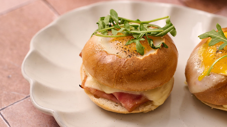 Croque madame bagel sliders on plate, topped with fresh arugula