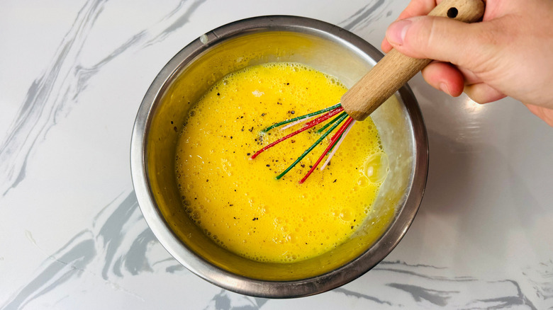 Hand whisking eggs in bowl