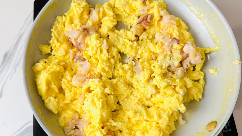Scrambled eggs with chunks of lobster in pan