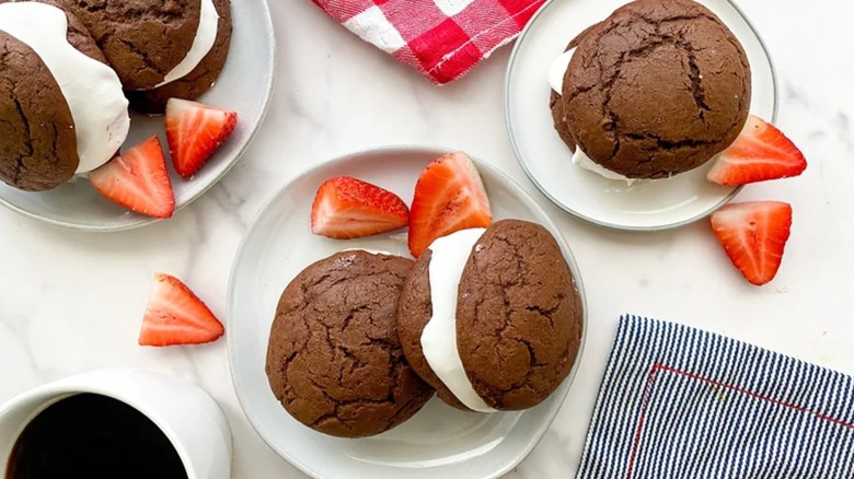 Plates with chocolate whoopie pies and sliced strawberries