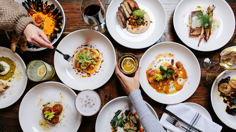 A table is set with many dinner plates with food on them.