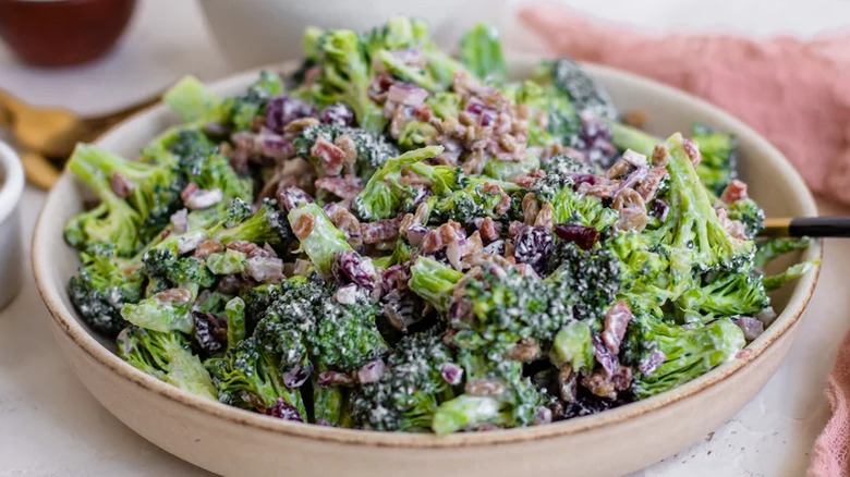 A bowl of broccoli salad with dried cranberries and bacon.