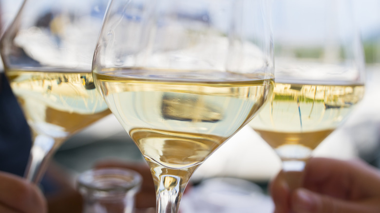 closeup white wine glasses clinking