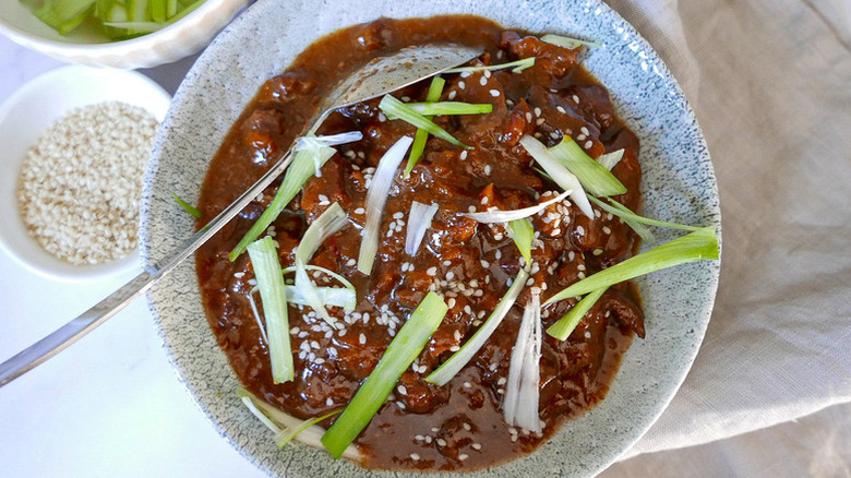Bowl of slow-cooked beef with green onions