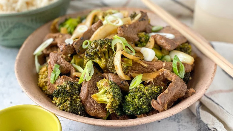 Bowl of beef and broccoli, garnished with chopped green onion