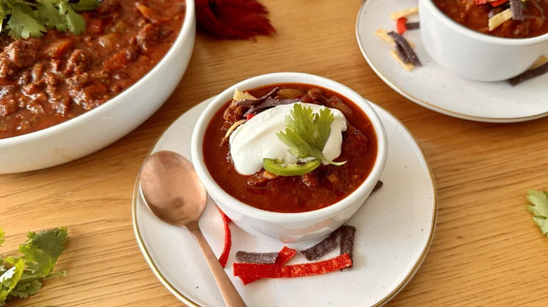 Bowl of chili topped with sour cream, tortilla strips, and fresh cilantro