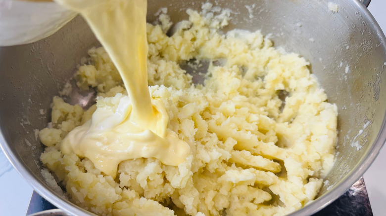 Cream mixture pouring into mashed potatoes
