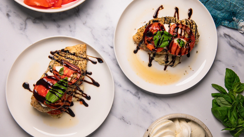 Two Caprese-stuffed chicken breasts on two white plates