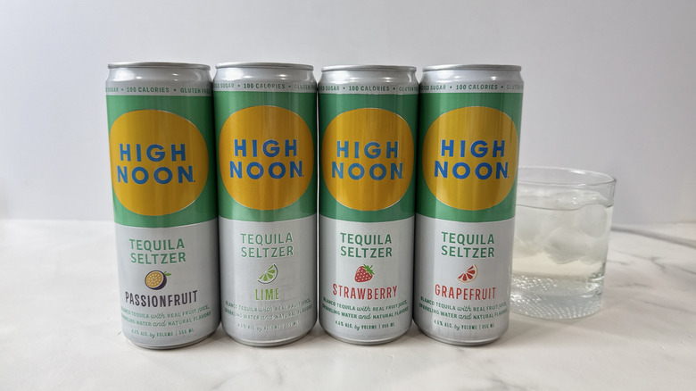 cans of High Noon tequila seltzers and glass with cocktail
