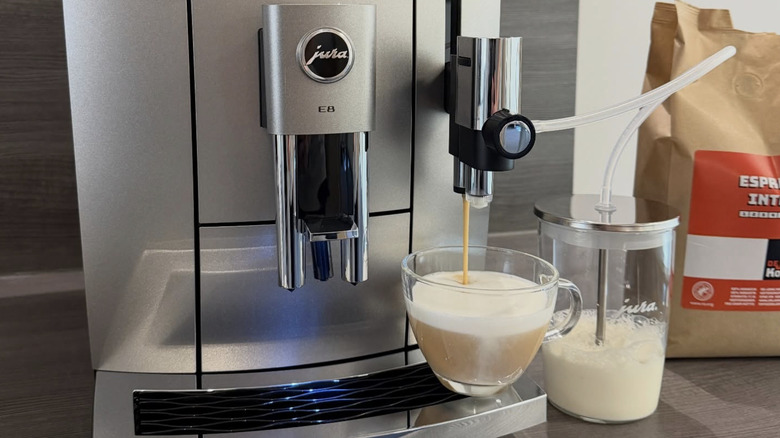 A Jura coffee machine on a counter pouring coffee into a clear cup