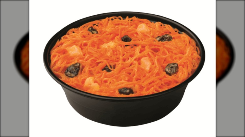 Carrot and raisin salad in black dish on white background