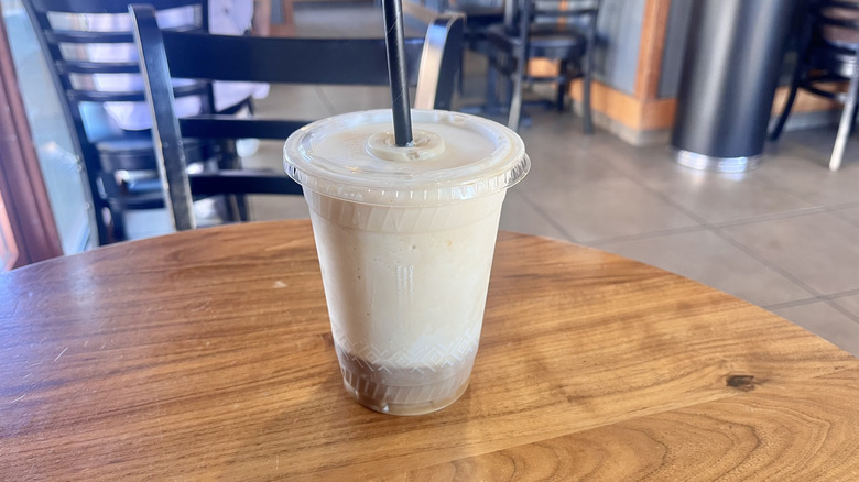 Peet's Coffee Protein Banana Cold Brew Smoothie on a table with a straw inside a plastic cup