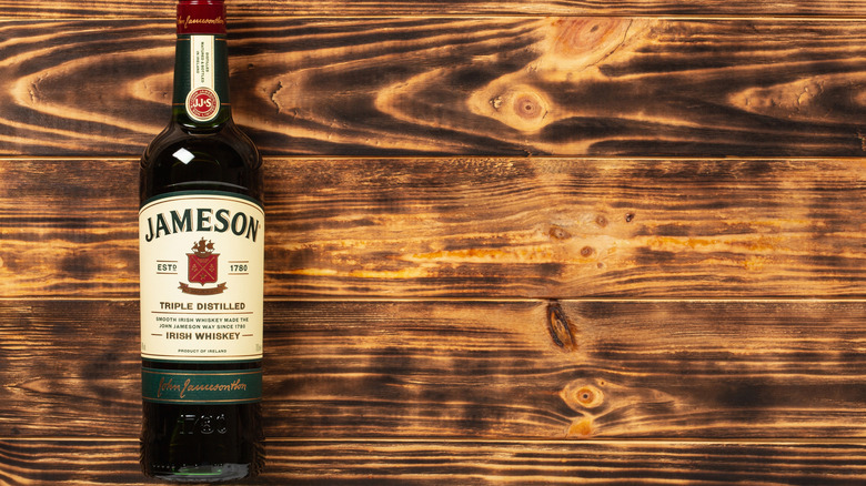 A bottle of Jameson shown against a plain wooden background