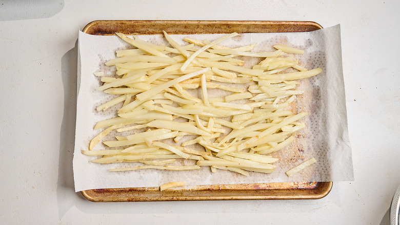 draining fried potatoes on a paper towel-lined tray