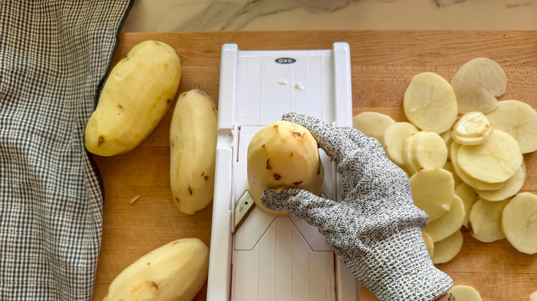 hand slicing potatoes on mandoline