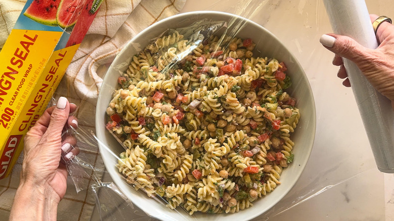 hands covering bowl of salad