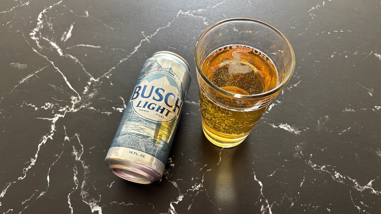Busch Light can with a glass of beer on a dark counter