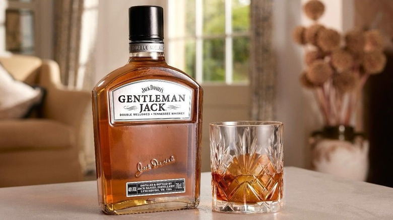 A bottle of Gentleman Jack sitting on a living room table next to a filled glass