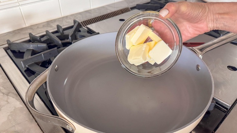 hand adding butter to pan