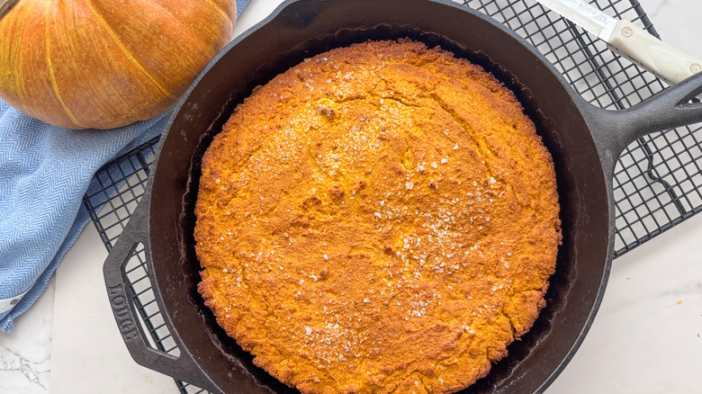 Pumpkin cornbread in skillet cooling on rack