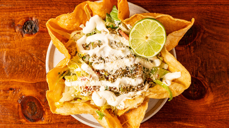 Taco salad in a tortilla bowl with a lime on top