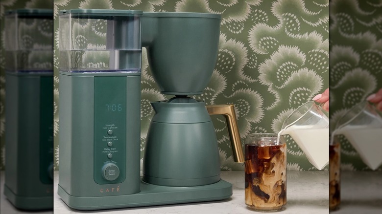 A forest green GE Café Specialty Drip Coffee Maker on a kitchen counter next to an iced coffee drink