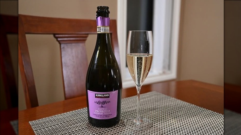 Bottle of Kirkland Signature Asolo Prosecco DOCG next to filled flute glass