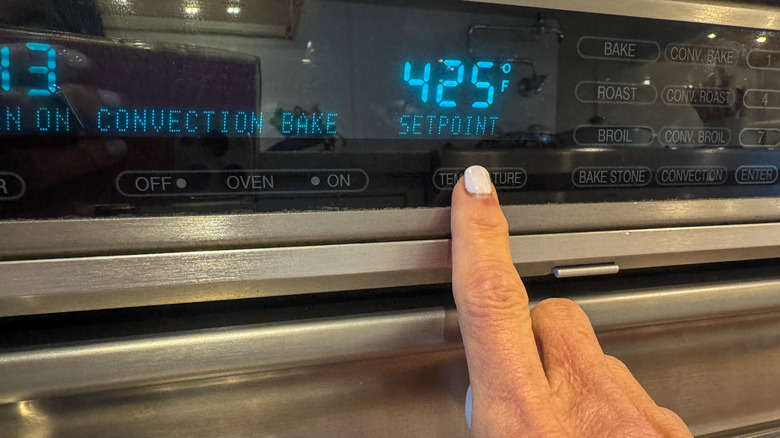Finger pressing button on oven control panel