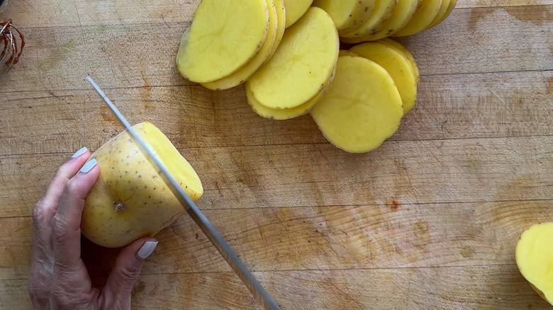 Slicing Yukon Gold potatoes on wooden board